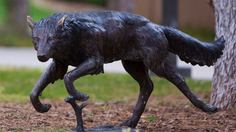 a bronze statue of a wolf running