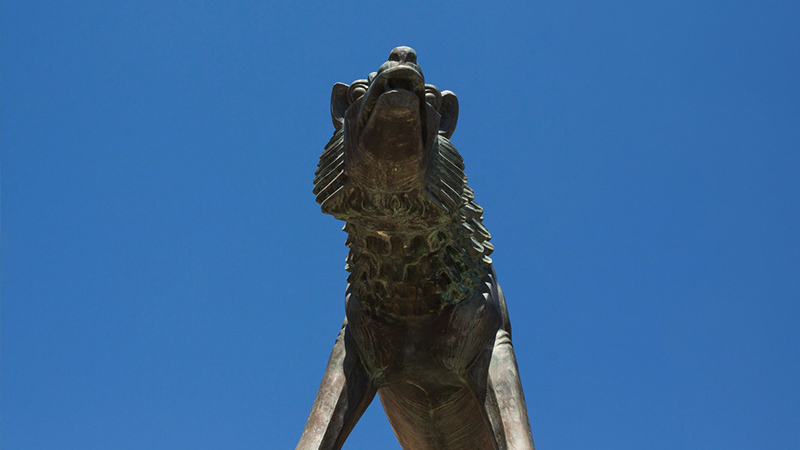 low angle photo of wolf statue in front of clear blue sky